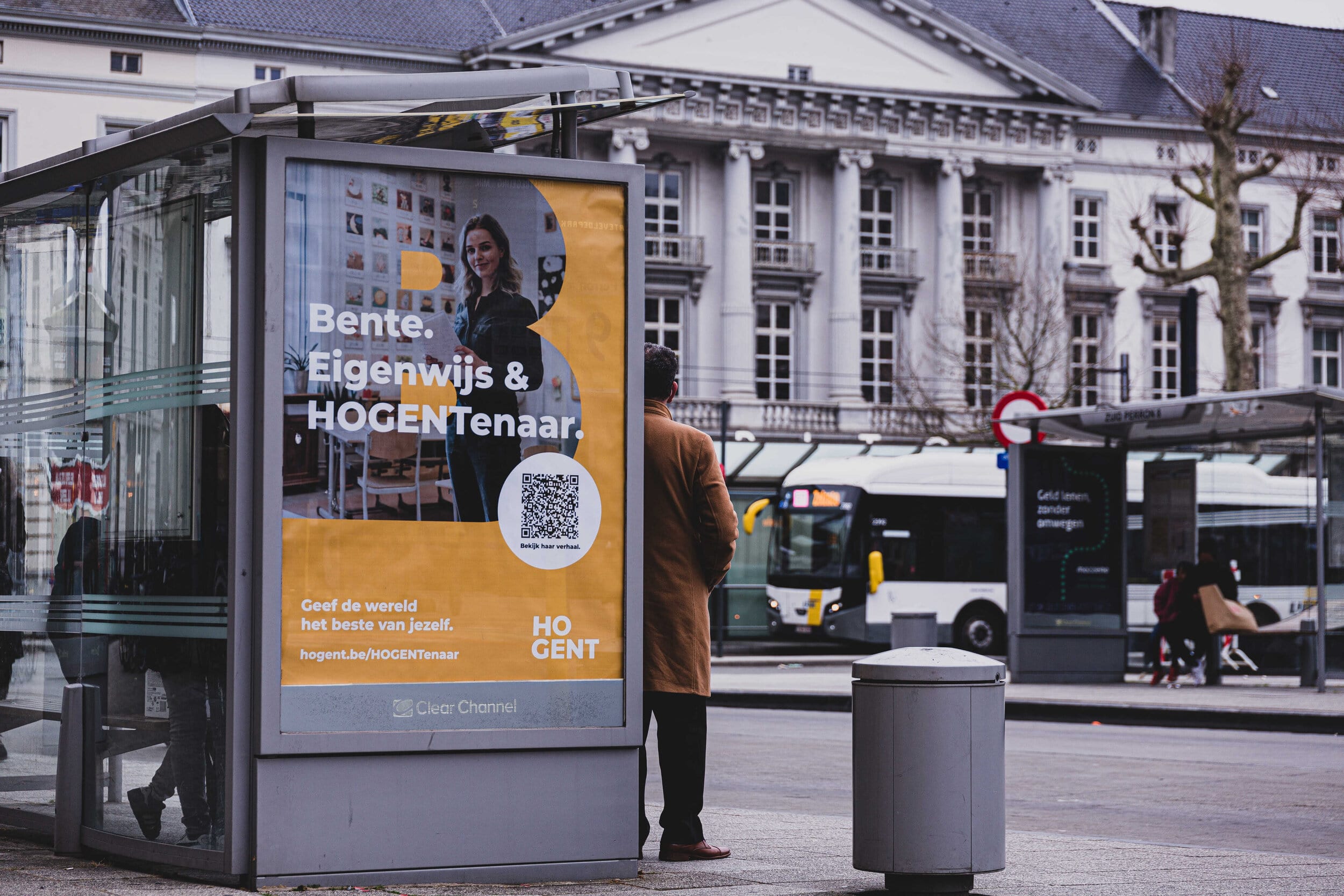 Bus shelter with a banner of HOGENTenaars advertising for children to study further for Teacher