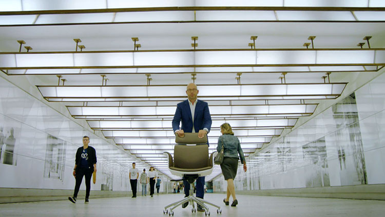 Person walks behind his office chair in the corridors of the building.